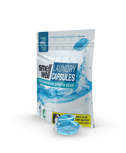 A package of SmellWell Laundry Capsules and 2 laundry capsules next to it (left tilt angle)