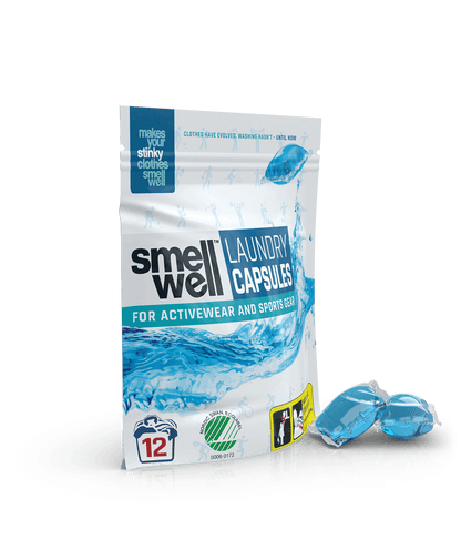 A package of SmellWell Laundry Capsules and 2 laundry capsules next to it (right tilt angle)